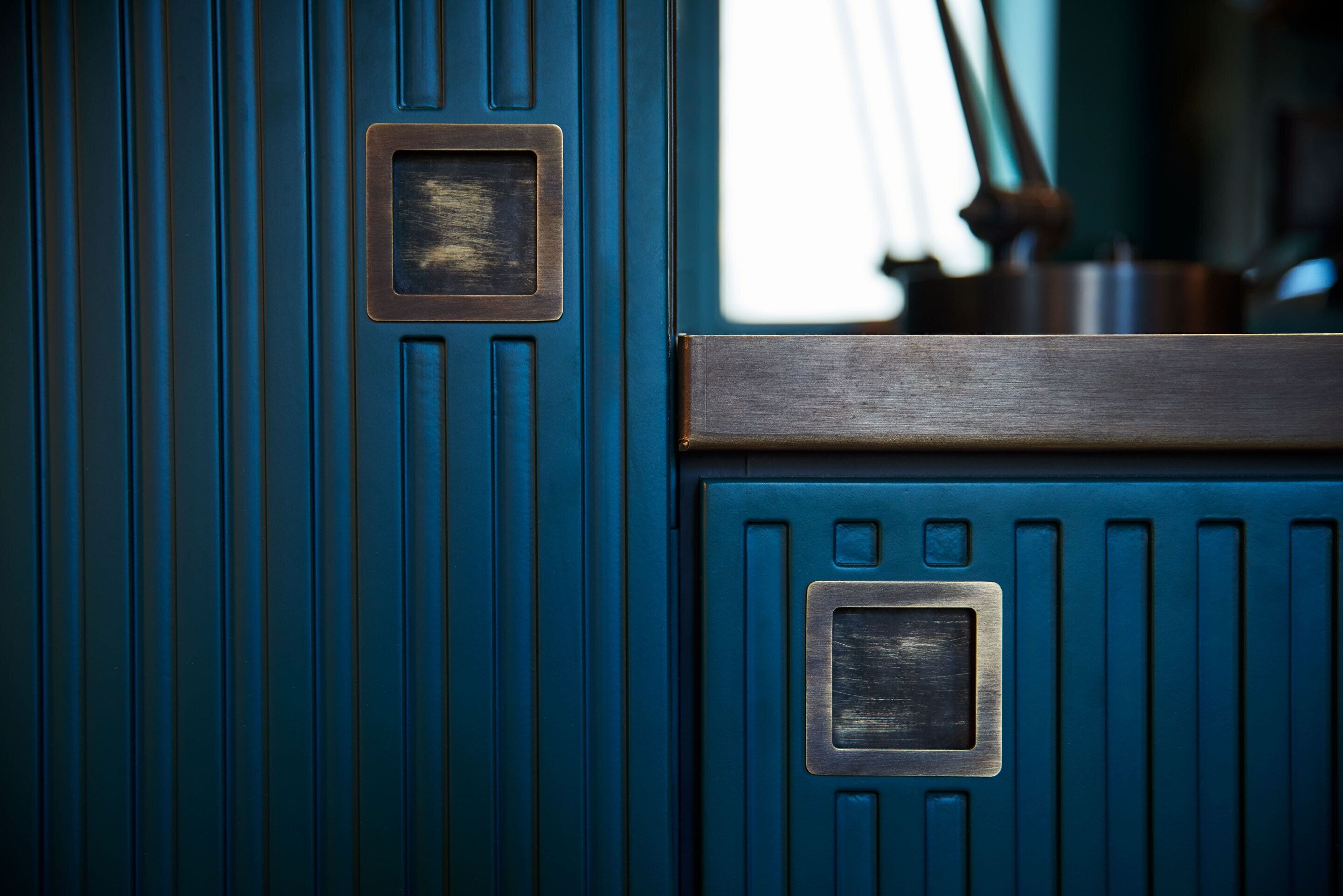 A close-up of a blue door with a metal handle and a rectangular metal plate.