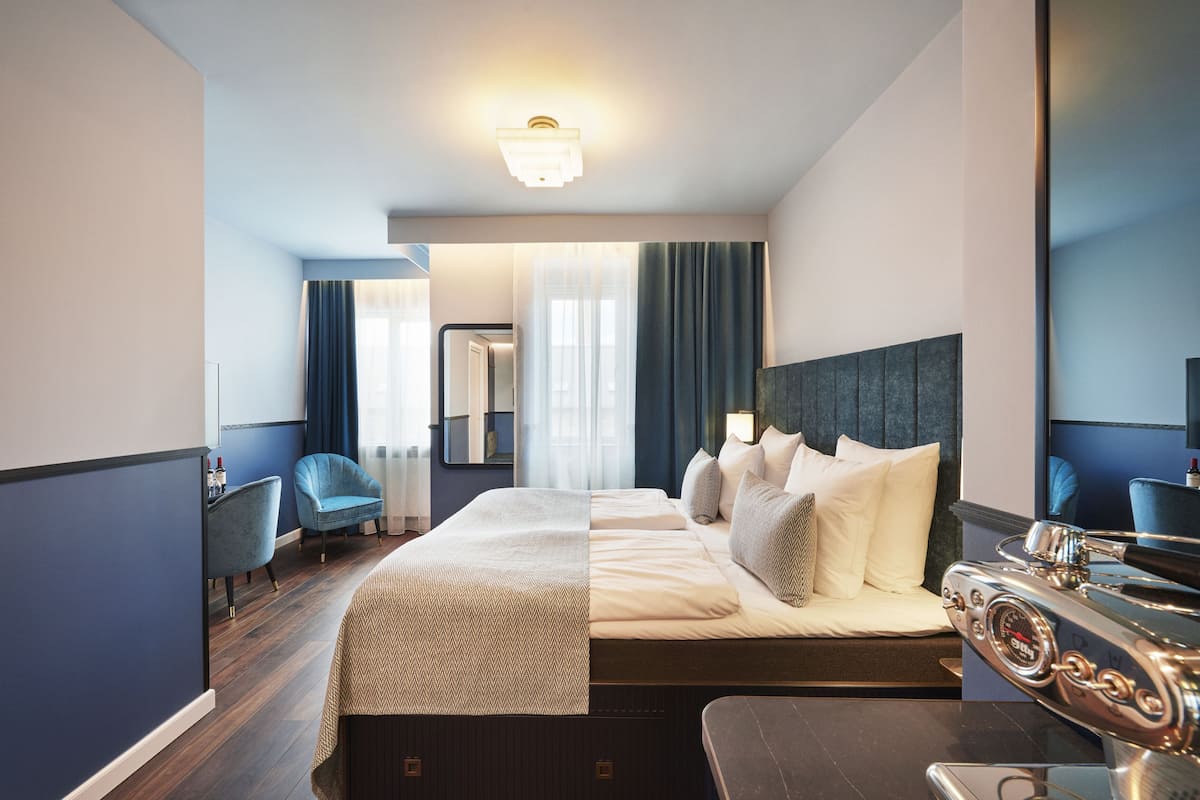 Una habitación de hotel con una cama grande, un escritorio, una silla y un espejo.