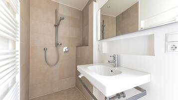 Un baño moderno con ducha, lavabo y espejo.