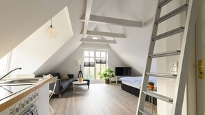 A modern loft bedroom with a skylight, a kitchen area, and a seating area. - Altstadt Apartments Verden - Andreasstraße (Verden)
