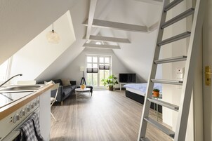 Quarto estilo loft moderno com claraboia, cozinha e área de estar.