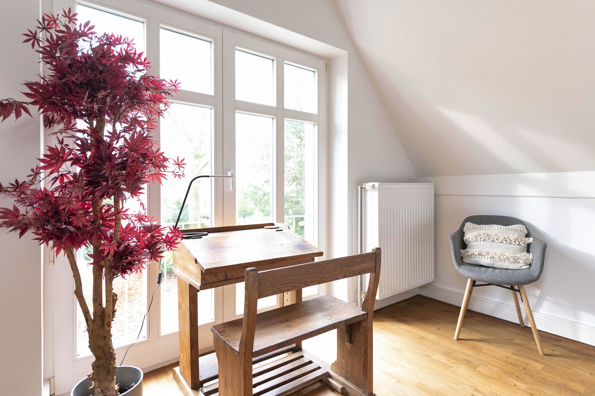 A room with a wooden table, a chair, a radiator, and a potted plant.