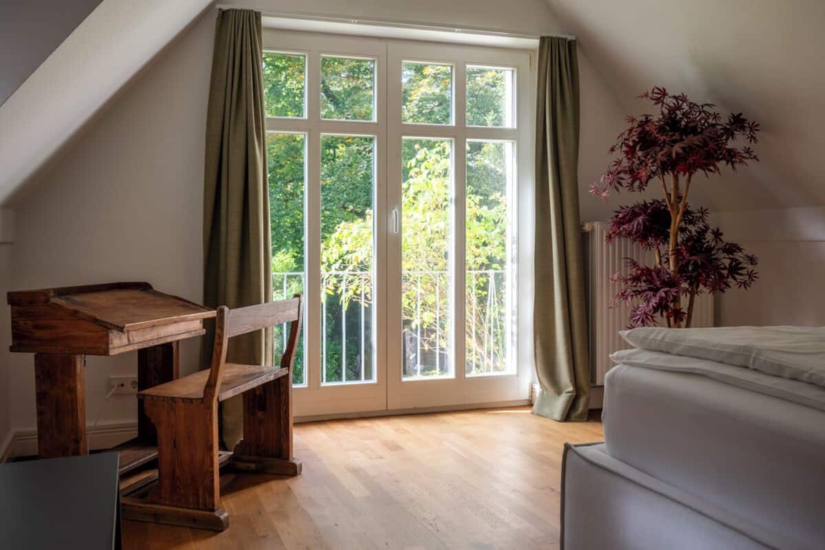 Un dormitorio con un ventanal grande, un escritorio de madera y una cama.