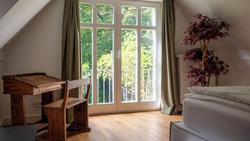 A bedroom with a large window, a wooden desk, and a bed.