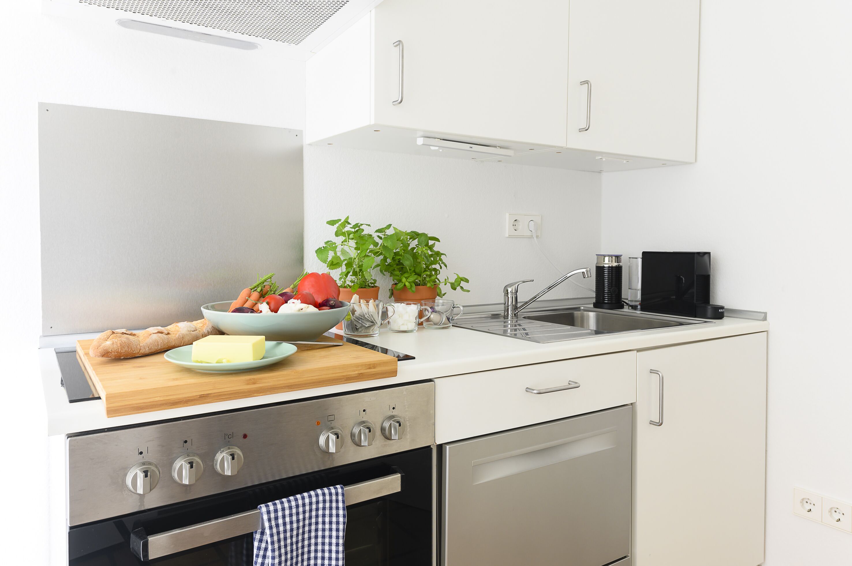 A modern kitchen with white cabinets, a stainless steel stove, and a sink.