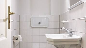 A small, compact bathroom with a toilet, sink, and a mirror.
