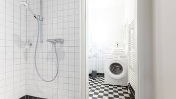 Un baño con ducha, lavadora y piso a cuadros.
