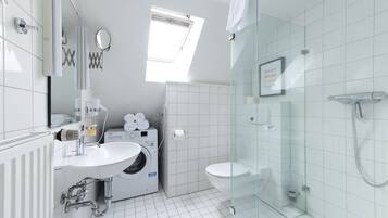 Une salle de bain moderne équipée d’un lavabo, d’un miroir, d’un porte-serviettes, d’une douche et de toilettes.