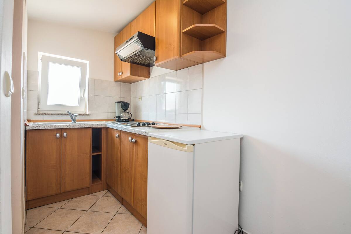 A kitchen with wooden cabinets, a white dishwasher, a stove, and a window.