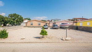 Zona residencial con casas, camino de grava y coches aparcados.