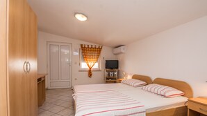 Un dormitorio con una cama grande, un armario de madera y un televisor sobre un mueble.