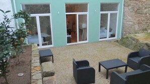 A patio area with outdoor seating and a stone wall. - Two-Bedroom Apartment (Porto)