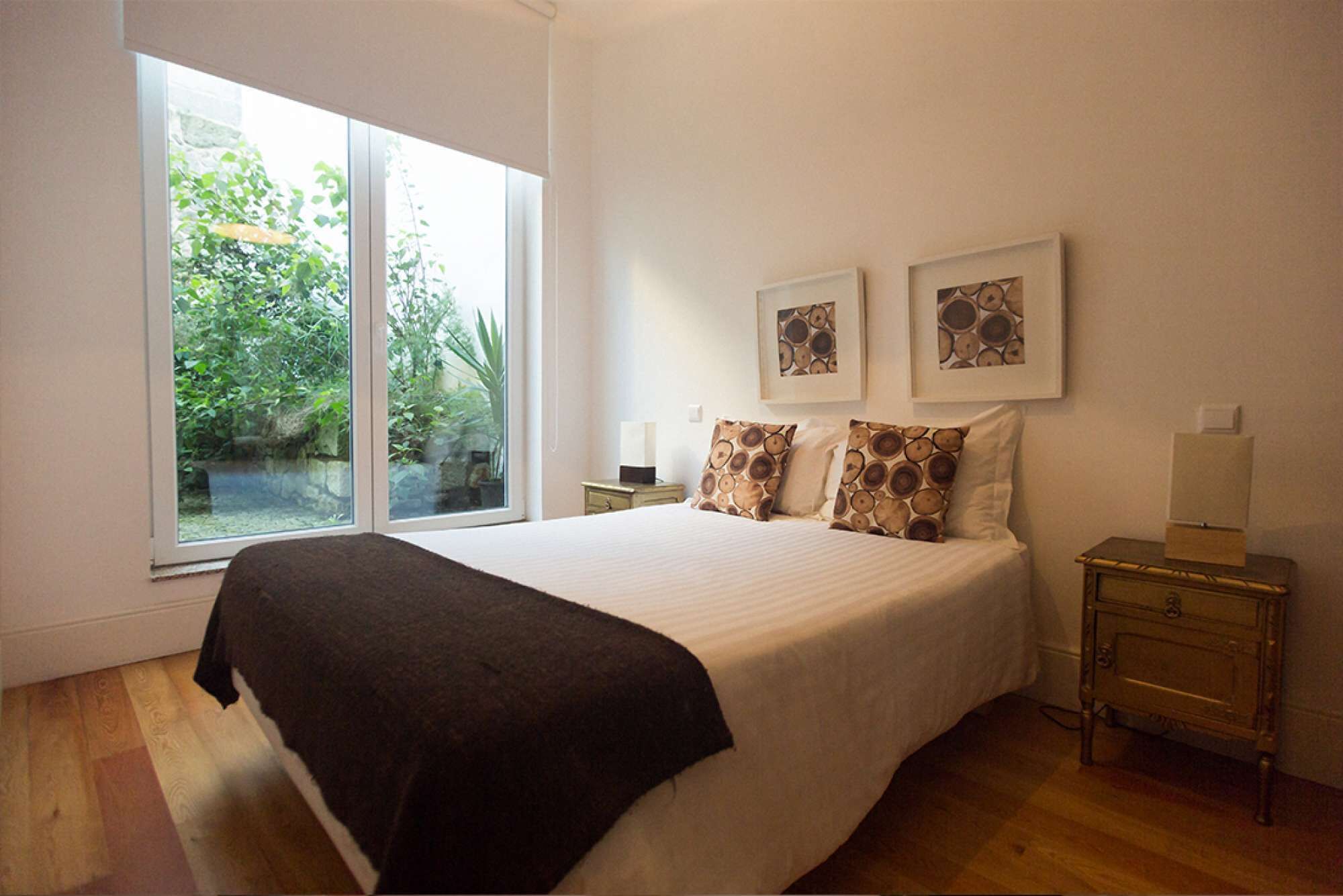 A bedroom with a large bed, a nightstand, a bedside table, and two framed pictures on the wall.