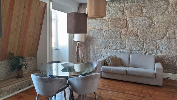 Una sala de estar moderna con una pared de piedra, una mesa redonda de vidrio y un sofá gris.