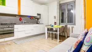 A modern kitchen with white cabinets, a built-in oven, and a dining area with a table and chairs. - GuestHost - Comfortable 50sqm apartment with tiled patio that can accommodate up to 4 people. Located on the ground floor of a modern building of recent construction, the apartment is equipped with private parking space for a motorbike (inside the patio) (Firenze)
