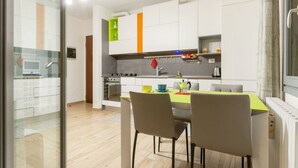 A modern kitchen with white cabinets, a dining table with chairs, and a visible stove. - GuestHost - Comfortable 50sqm apartment with tiled patio that can accommodate up to 4 people. Located on the ground floor of a modern building of recent construction, the apartment is equipped with private parking space for a motorbike (inside the patio) (Firenze)
