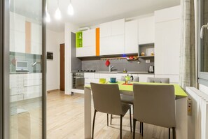 Une cuisine moderne avec des meubles blancs, une table à manger avec des chaises et une cuisinière bien visible.