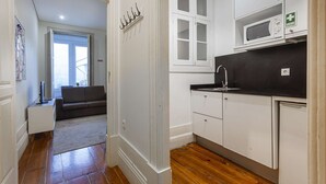 Une cuisine moderne avec des meubles blancs, un plan de travail noir et un four à micro-ondes. Il y a une fenêtre au-dessus de l’évier et une porte qui donne sur une autre pièce.