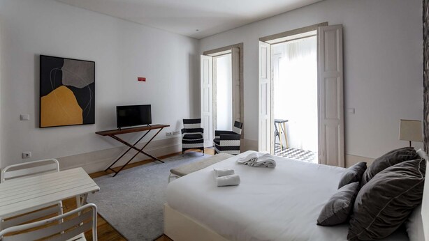 Une chambre d’hôtel avec un lit, un téléviseur posé sur un meuble, une petite table, deux chaises et un tableau accroché au mur.