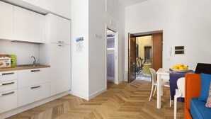 A compact kitchen with white cabinets, a wooden countertop, and a herringbone-patterned floor. - Casa 80 (Sorrento)