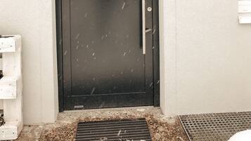 L’entrée d’un hôtel, avec une porte noire, une enseigne indiquant « Entrée – Enregistrement » et une autre mentionnant « Haute sécurité ».