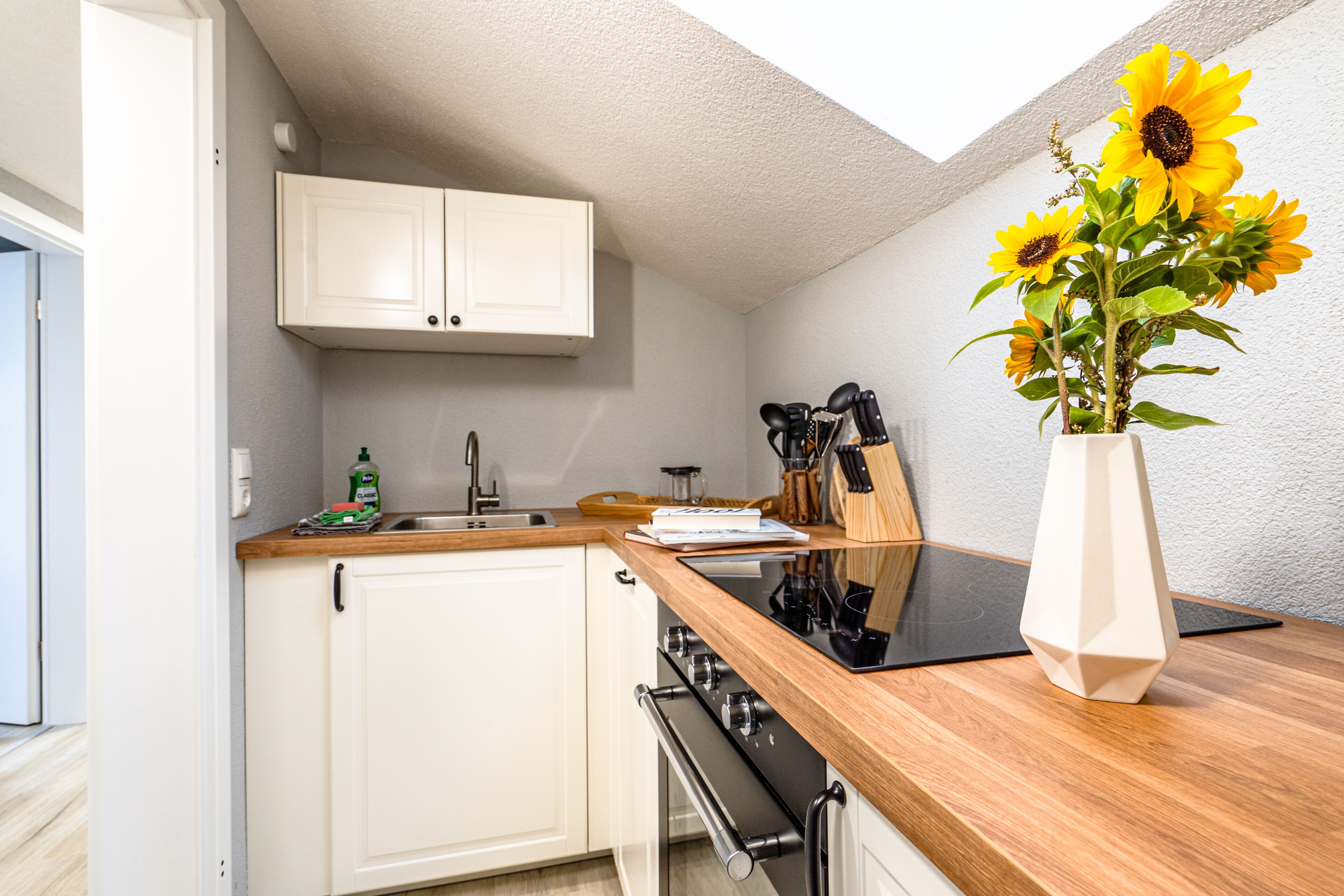 A modern kitchen with white cabinets, a wooden countertop, and a built-in oven.