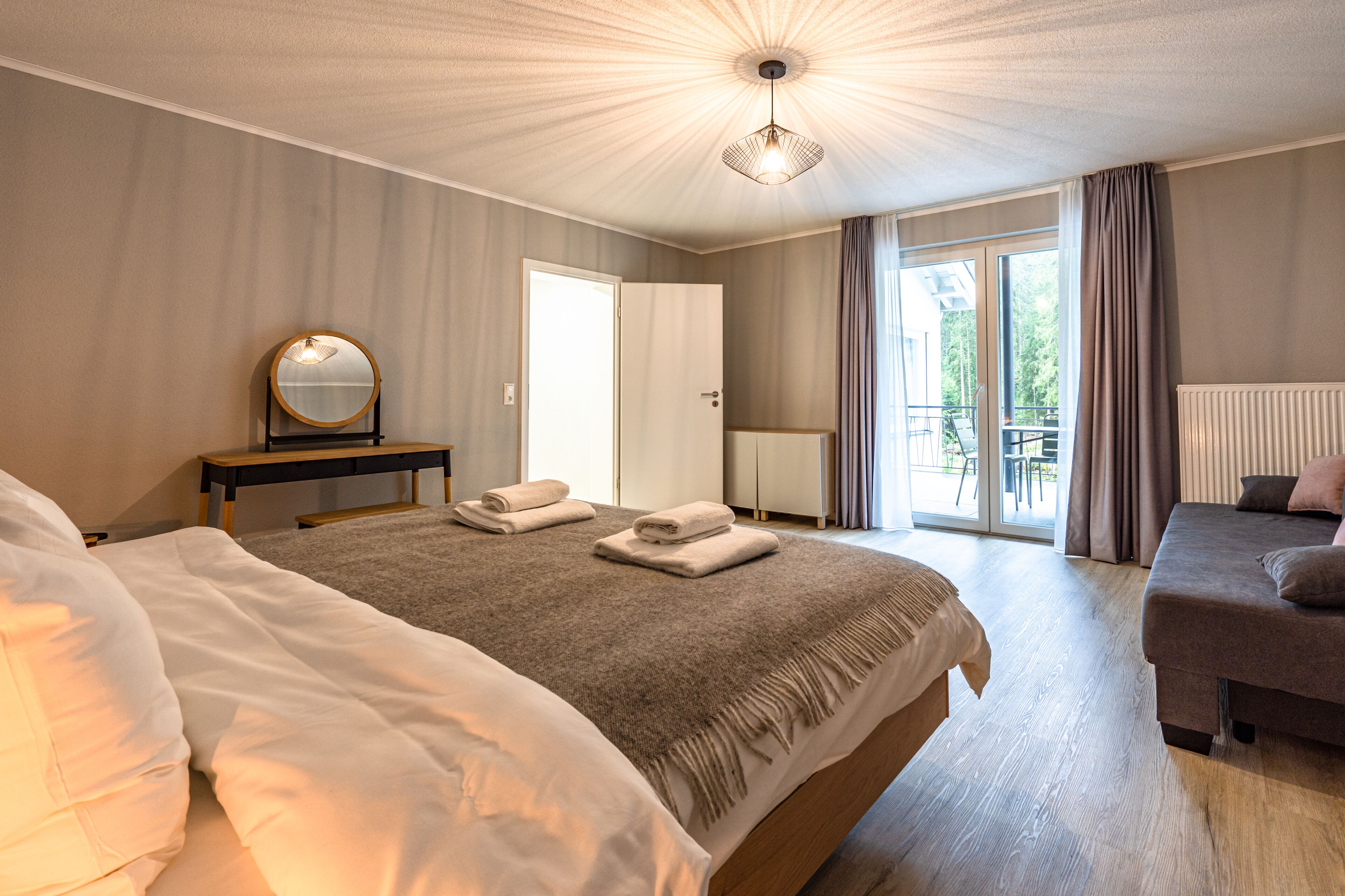 Une chambre d’hôtel avec un grand lit, un lit plus petit, un bureau avec un miroir et une vue sur l’extérieur.