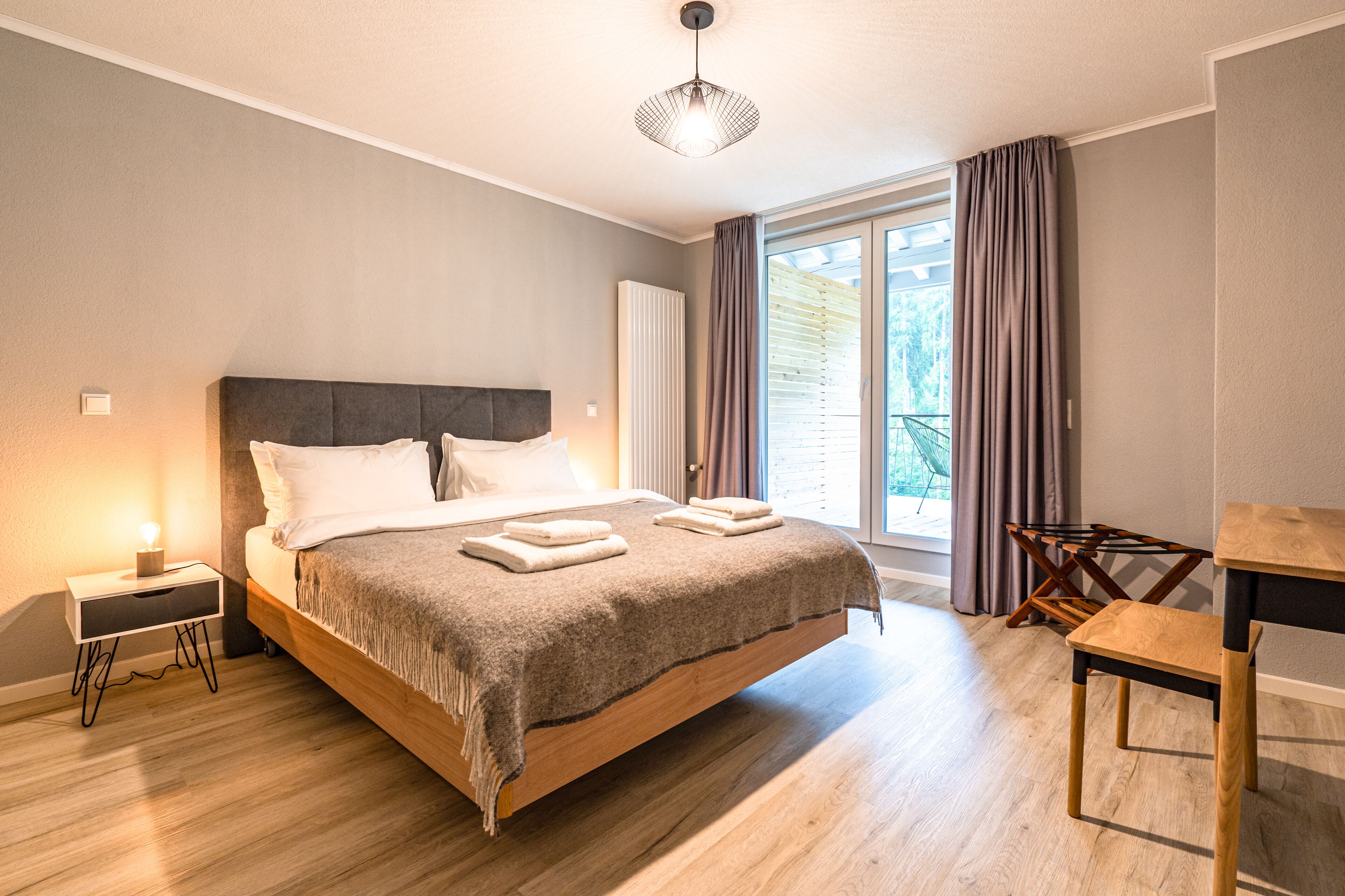 Une chambre à coucher moderne avec un lit en bois, une table de chevet et une petite chaise en bois.