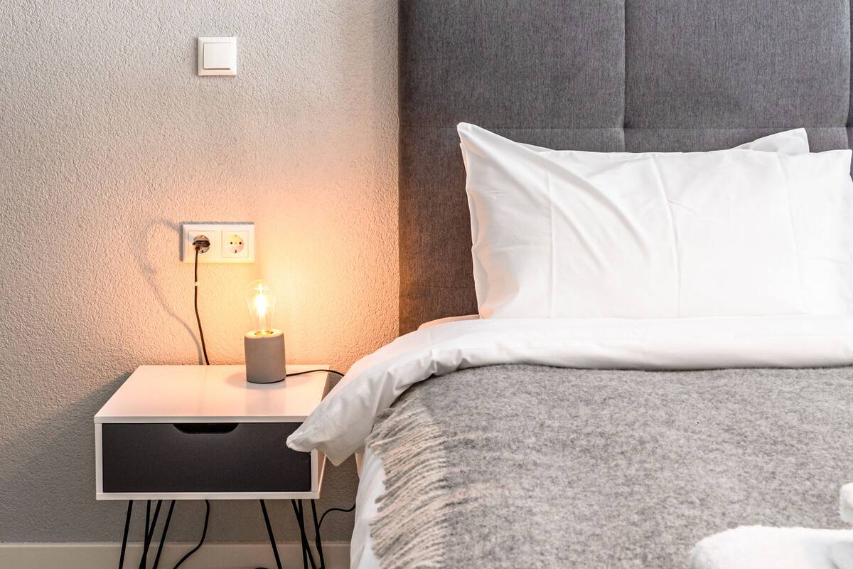 Ein ordentlich eingerichtetes Schlafzimmer mit Bett, Nachttisch und Lampe.