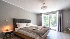 A modern bedroom with a large bed, a bedside table with a lamp, and a view of the outdoors through a window. - stuub langenbach (Titisee-Neustadt)