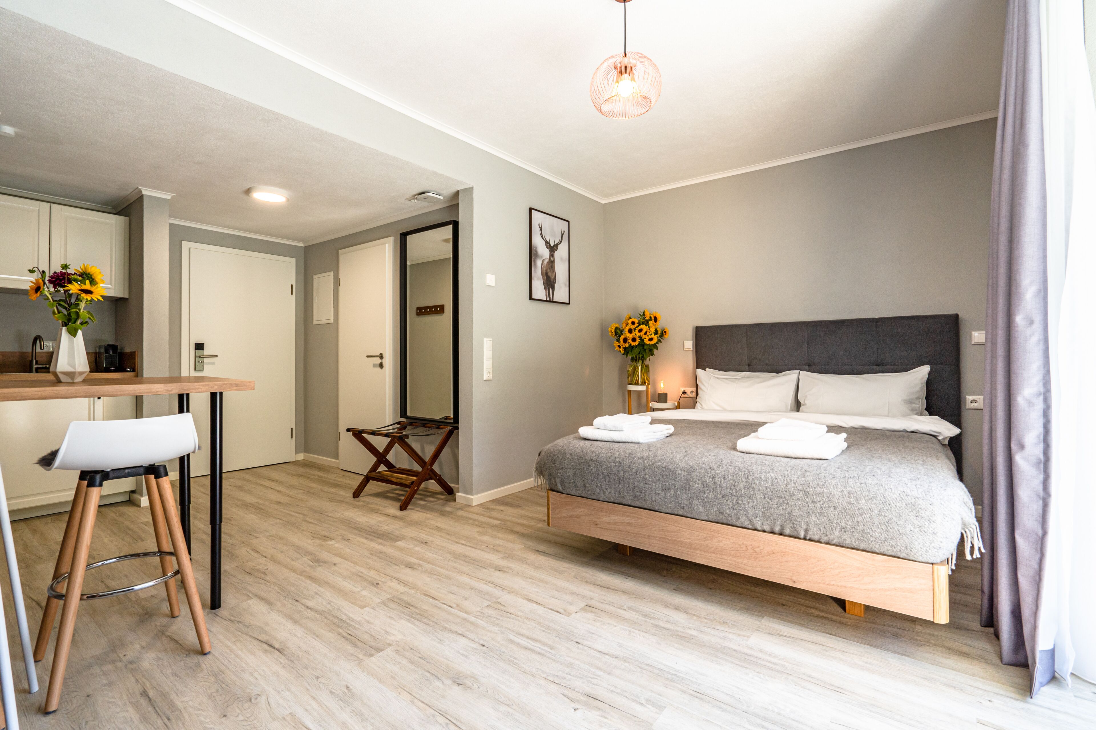A modern bedroom with a bed, bedside table, and a small stool.