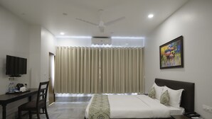 A hotel room with a bed, bedside table, desk, chair, and a television. - Central Hotel (Phuntsholing)