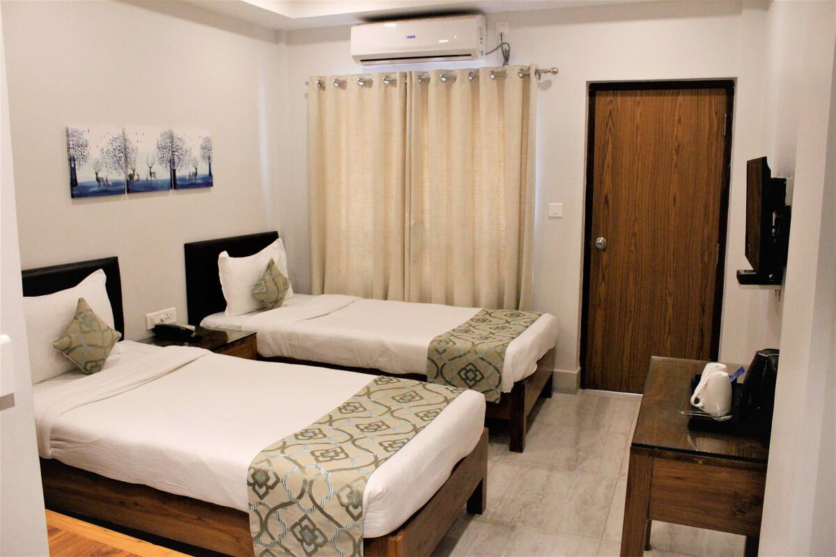 A hotel room with two beds, a wooden desk, a coffee maker, and a TV.