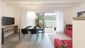 Ein modernes Wohnzimmer mit Essbereich, einem roten Sofa und einem Fernseher an der Wand.