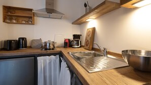 Eine kompakte Küche mit Spüle, Kaffeemaschine, Wasserkocher und kleinem Kühlschrank.