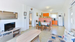 Un salon moderne comprenant un téléviseur, un meuble de rangement pour les appareils multimédias et un coin repas avec une table et des chaises.