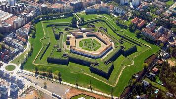 Vista aérea de un gran complejo fortificado con múltiples muros concéntricos y zonas verdes.