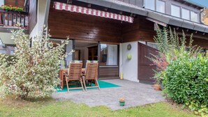 Une maison à deux étages avec un balcon, une terrasse couverte et une pelouse verdoyante.