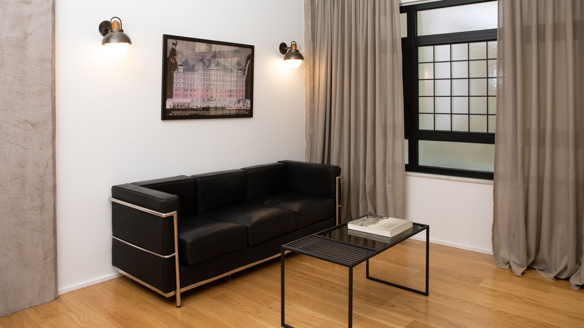 Un soggiorno moderno con un divano in pelle nera, un piccolo tavolino da caffè nero e un quadro incorniciato appeso al muro.