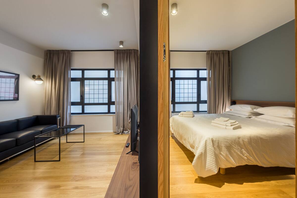 A modern hotel room with a large bed, a sofa, and a TV.