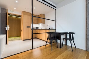 Una cocina moderna con armarios de madera, encimera negra y zona de comedor con mesa y sillas.