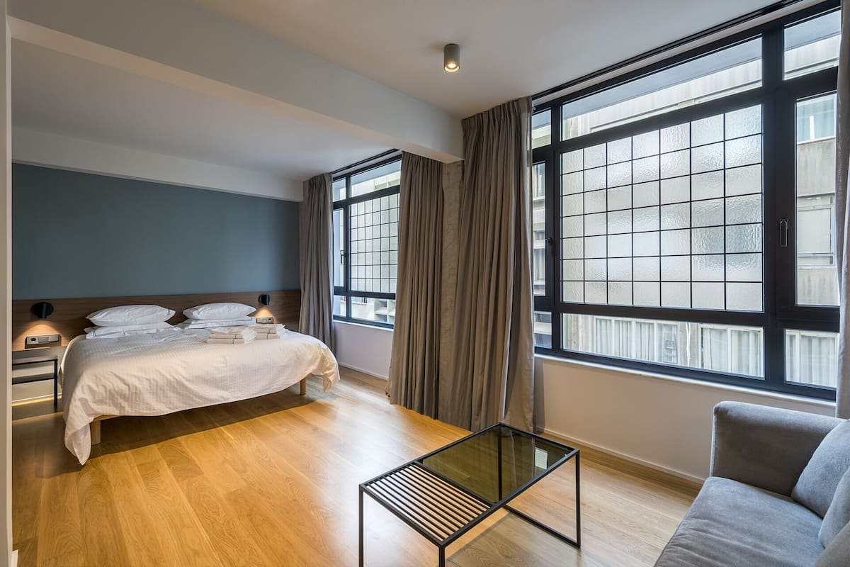 A hotel room with a bed, bedside table, lamp, and a glass coffee table.
