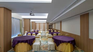 A conference room with rows of tables, chairs, and a projector on the ceiling.