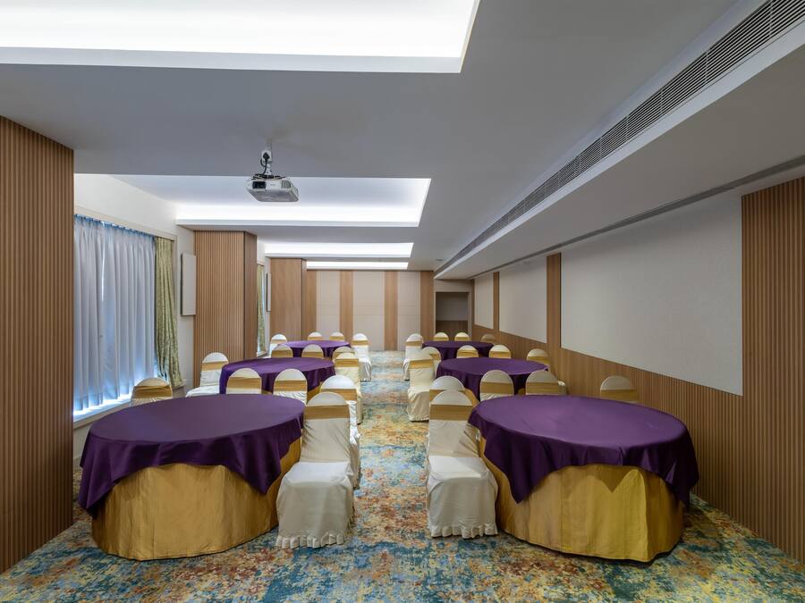 A conference room with rows of tables, chairs, and a projector on the ceiling.
