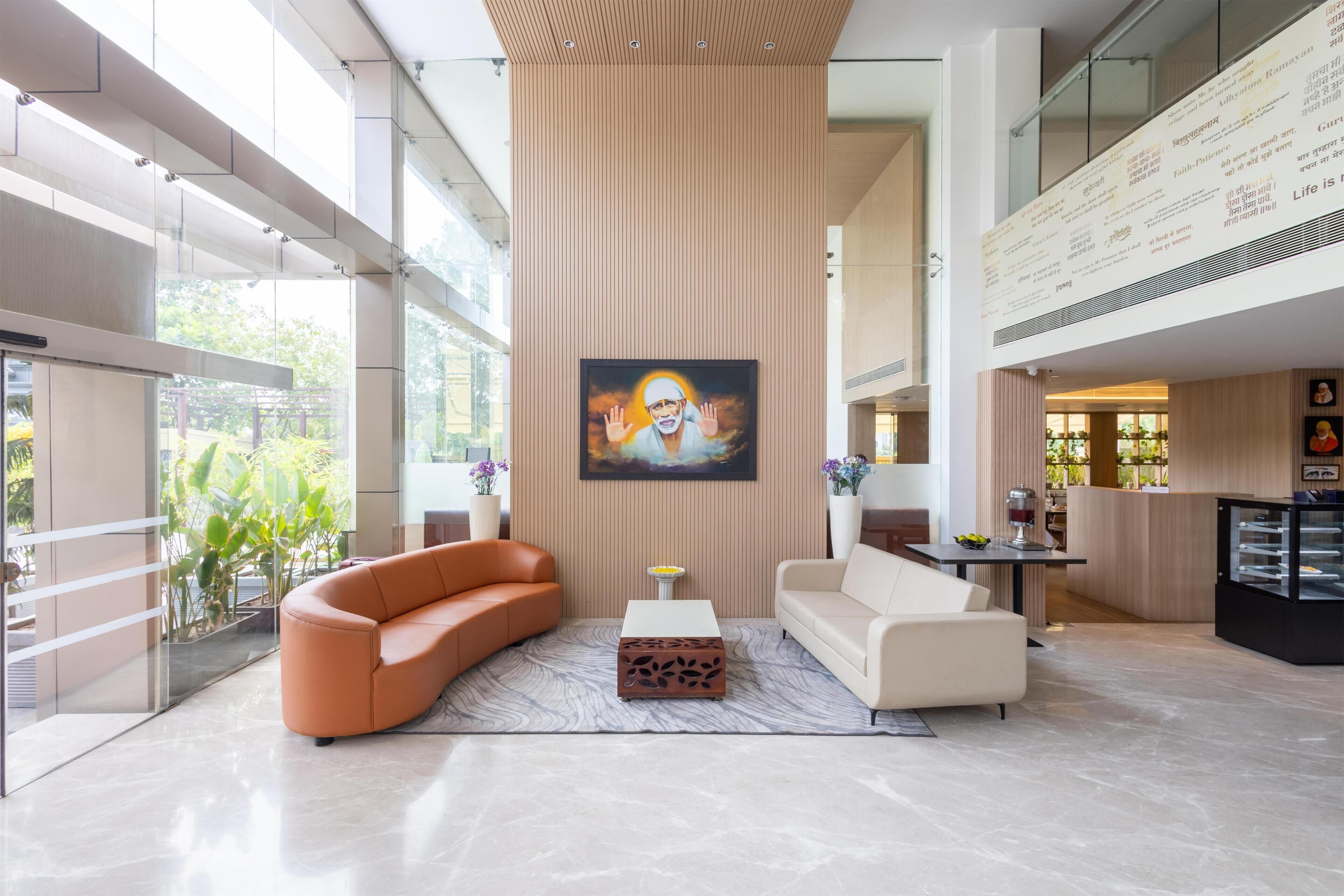 Een moderne lobby met een groot schilderij, twee banken, een salontafel en een glazen scheidingswand.