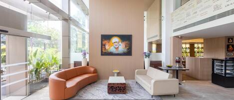 Een moderne lobby met een groot schilderij, twee banken, een salontafel en een glazen scheidingswand.