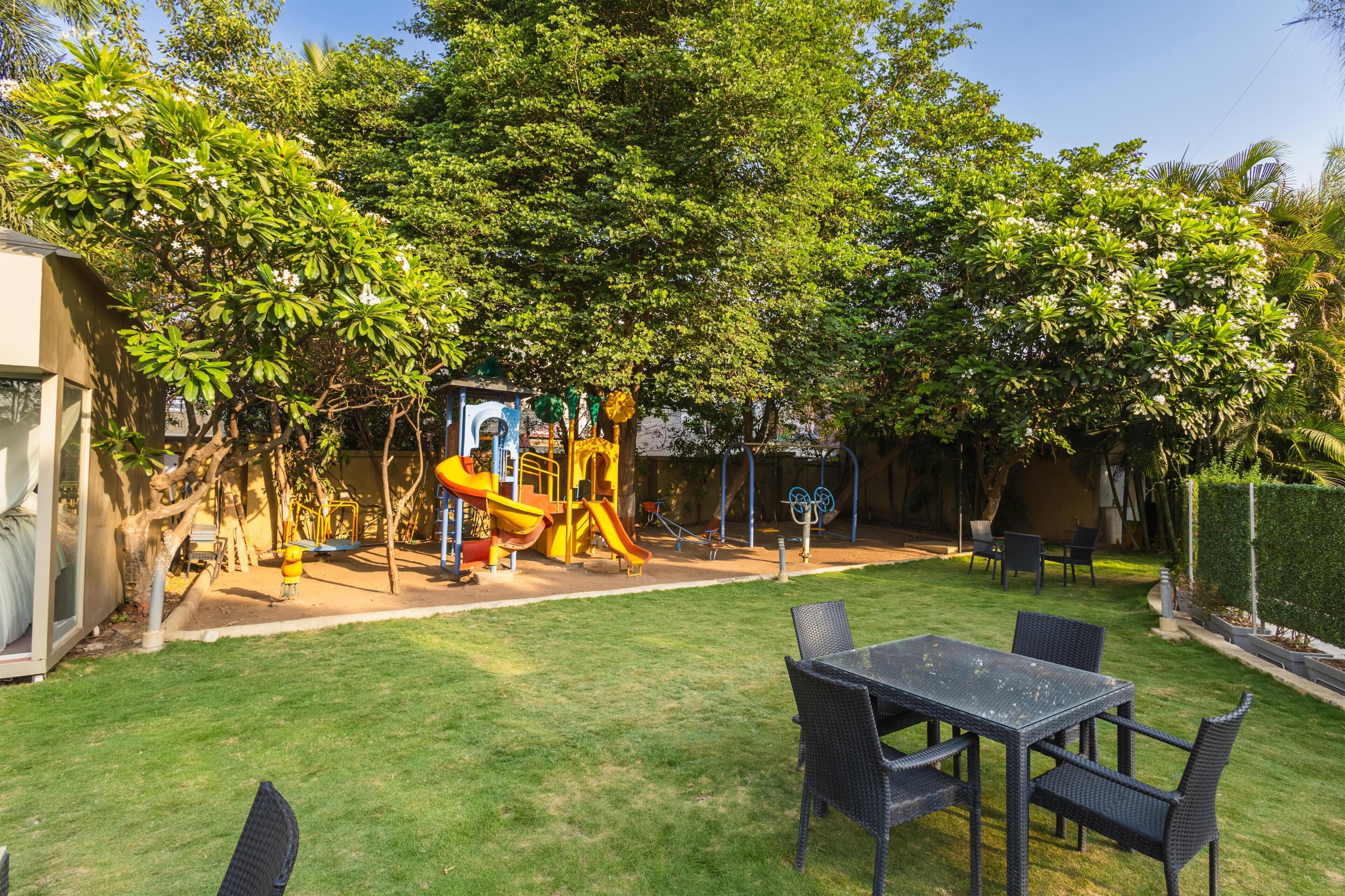 A backyard with a play area, a table with chairs, and a house.