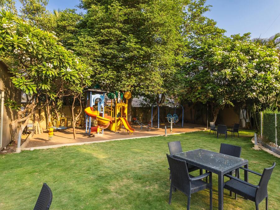 A backyard with a play area, a table with chairs, and a house.