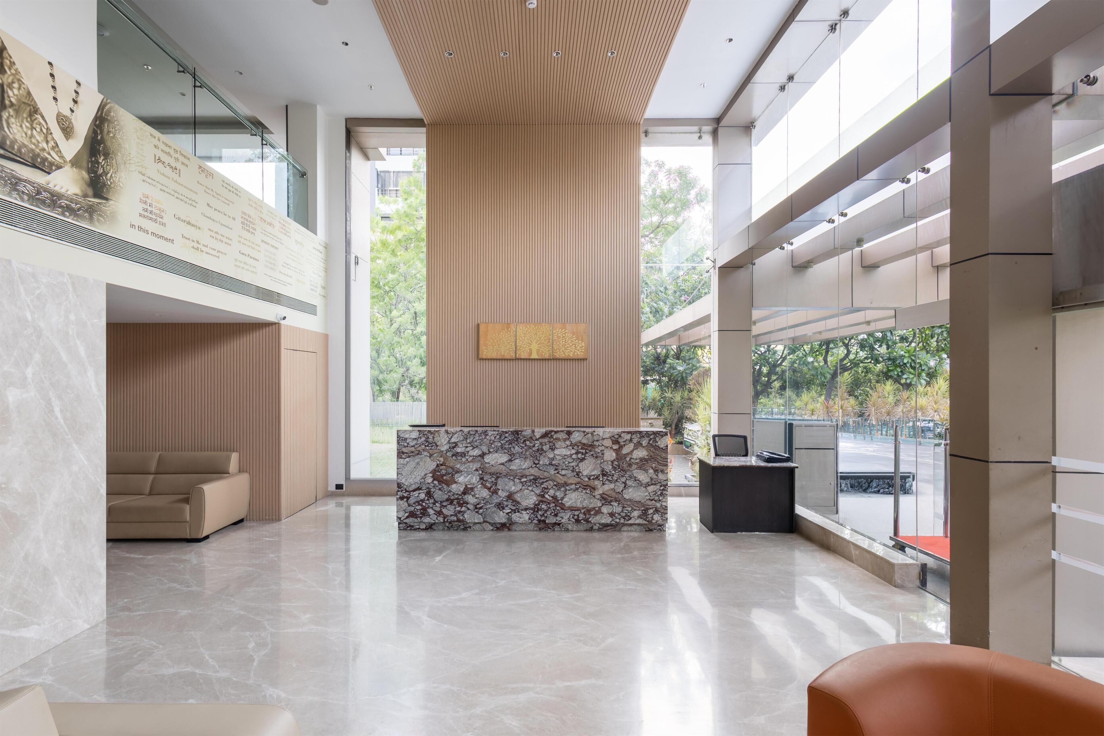 A modern lobby with a reception desk, a sofa, and a large window.