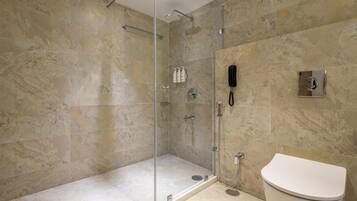 A bathroom with a glass-enclosed shower, a toilet, and a wall-mounted phone.
